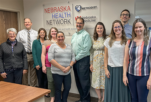 Nebraska Health Network team posing for photo in front of NHN sign